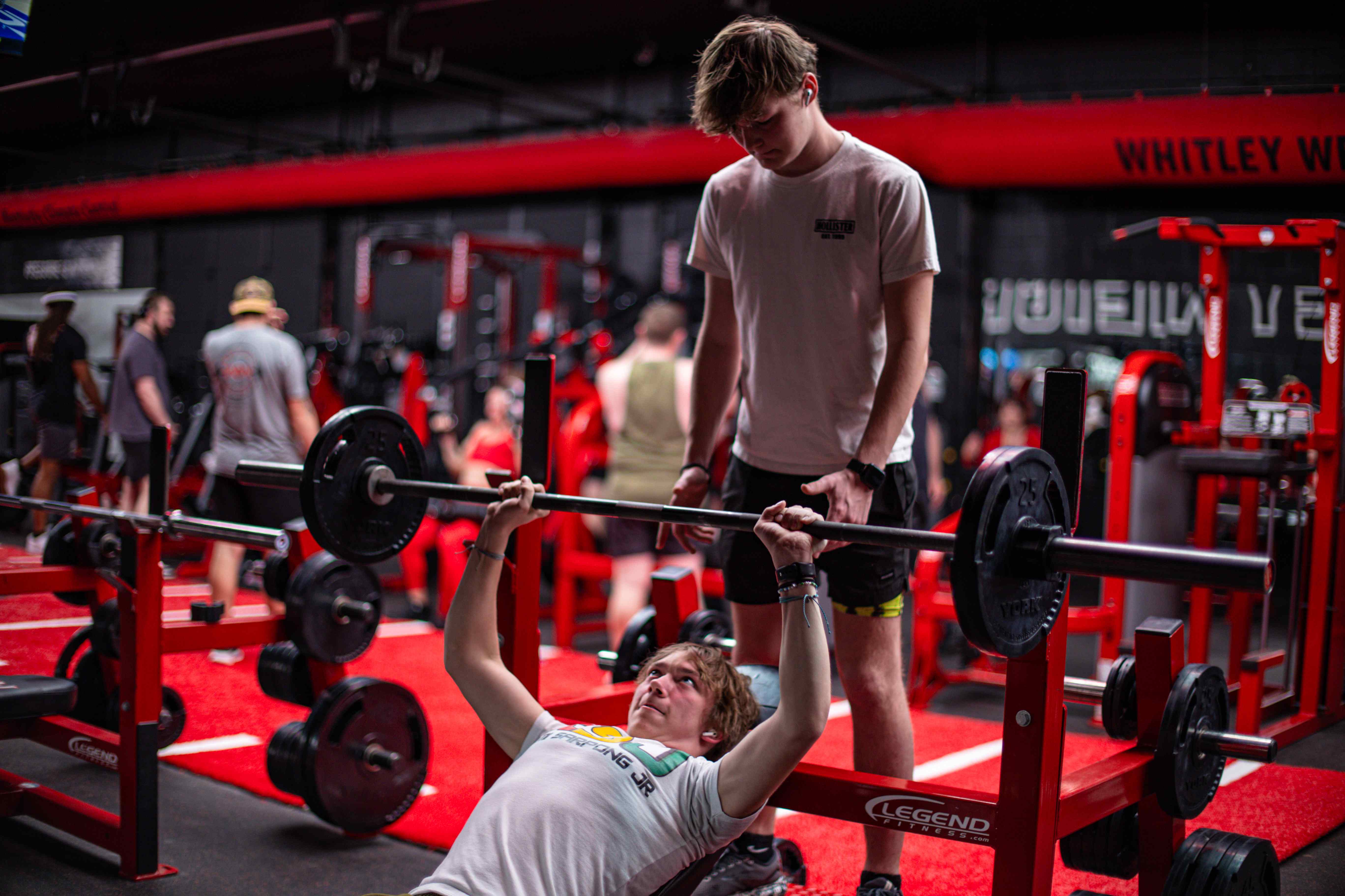 A lifter bench pressing with a training partner spotting