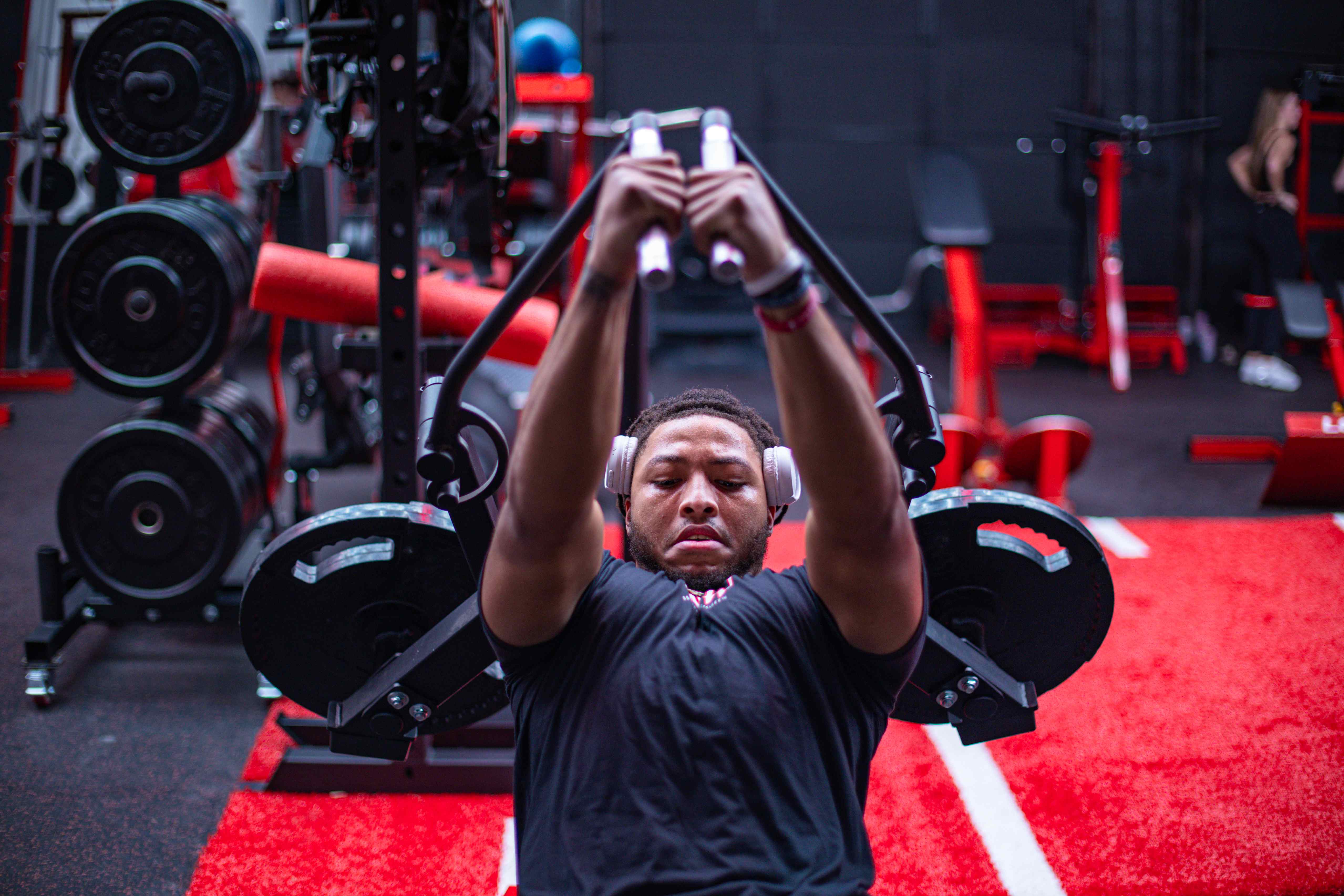 Member training on a plate-loaded chest press on the red turf