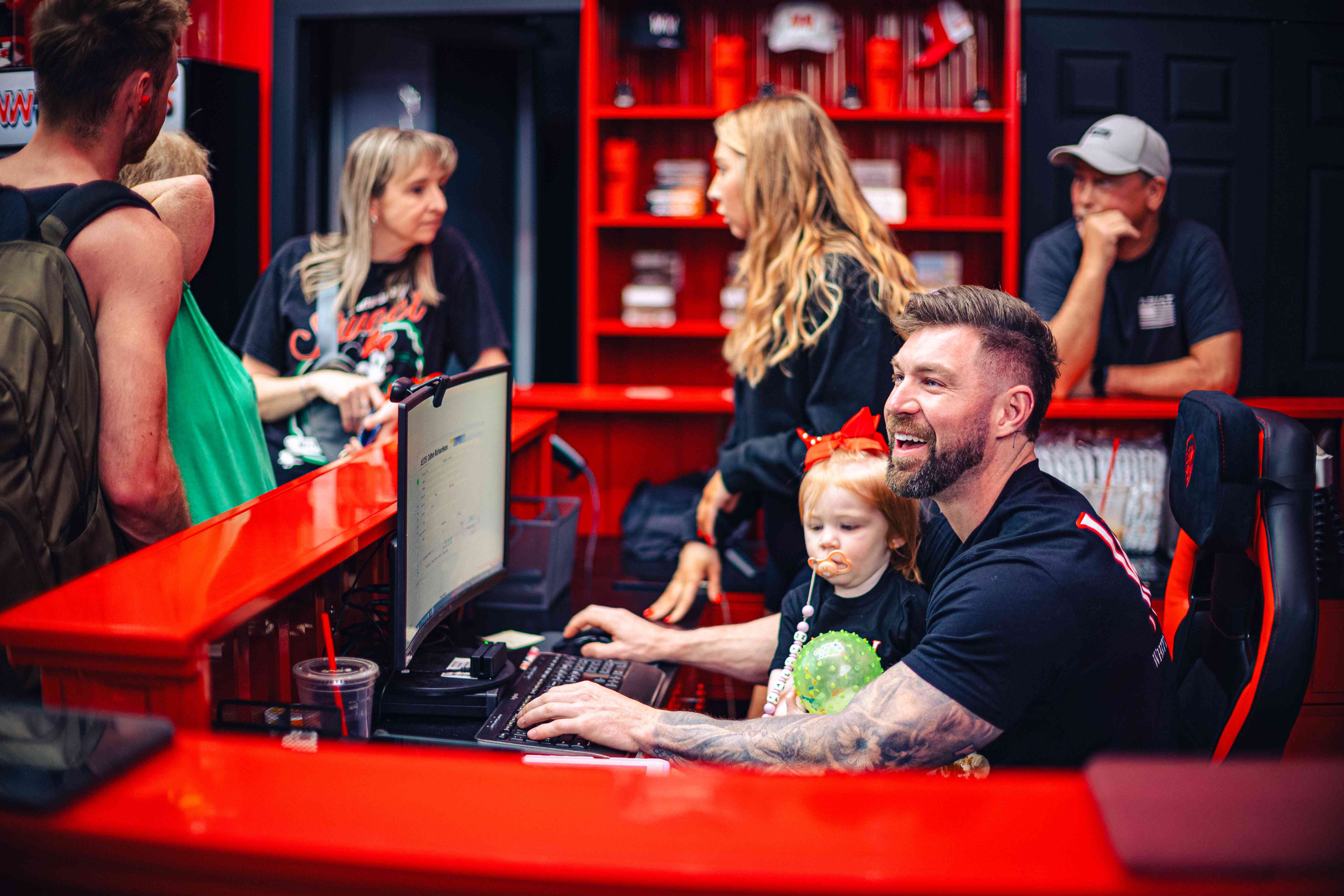 Owner checking in members at the red front desk with his daughter