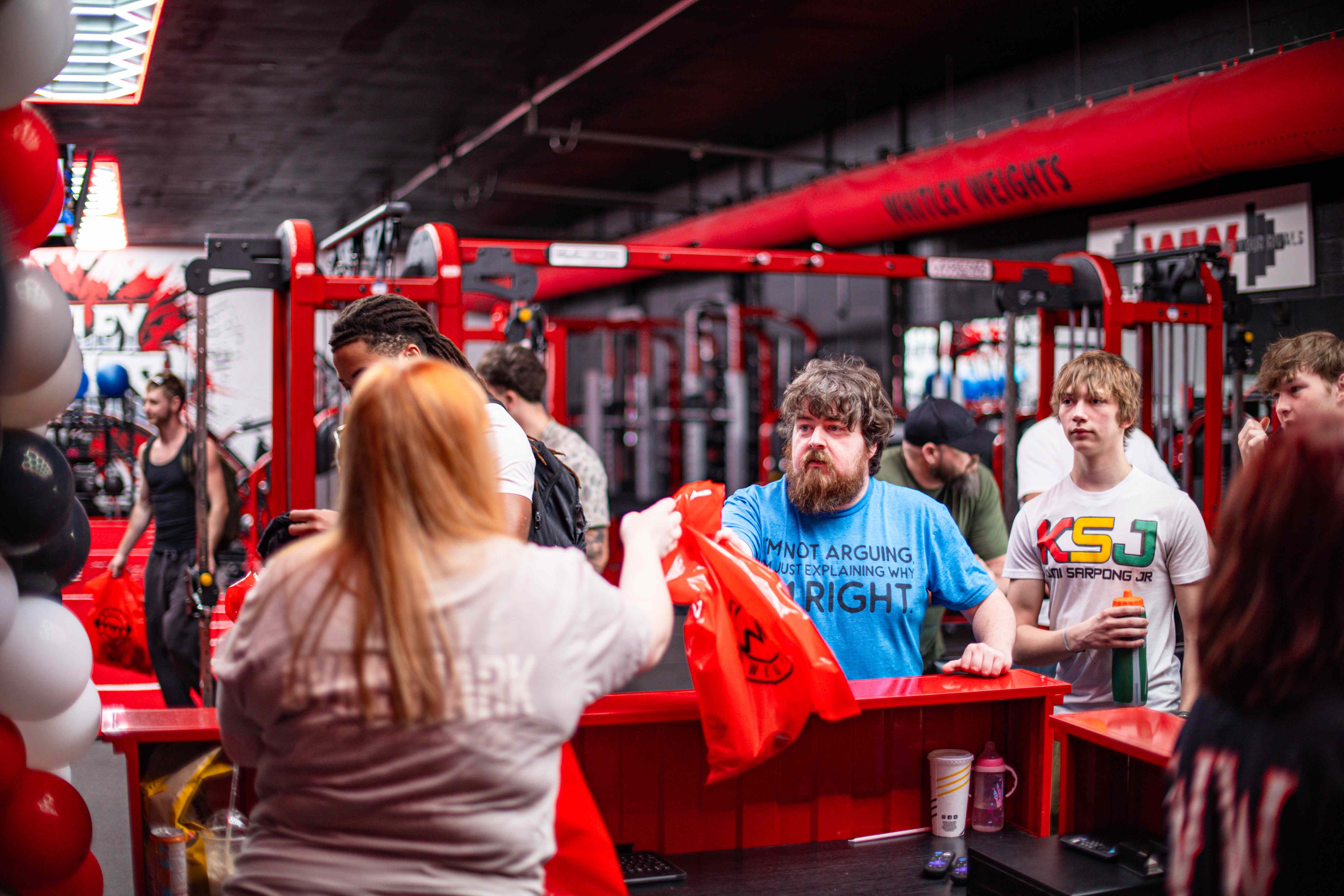 Members receiving red Whitley Weights bags at an event