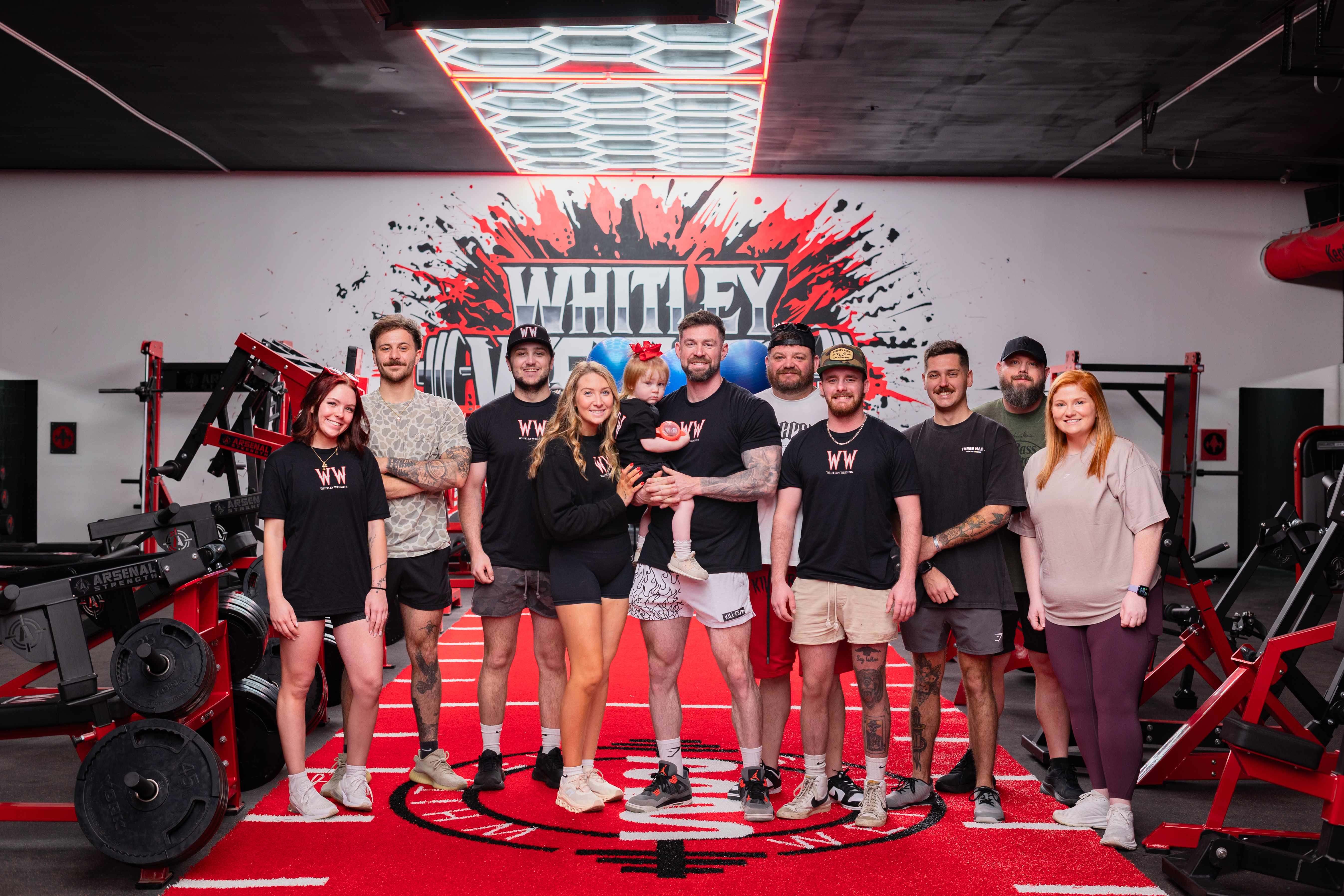 The Whitley Weights team on the red turf in front of the splatter mural